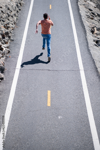 Back view of man running on the road. Athletic young man running outdoor.
