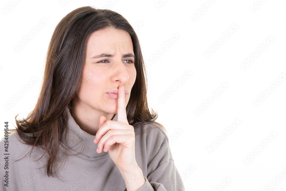 Cute mysterious woman showing silence shh sign holding finger on lips having secret isolated on white background Cute mysterious woman showing silence shh sign holding finger on lips having secret isolated on white background