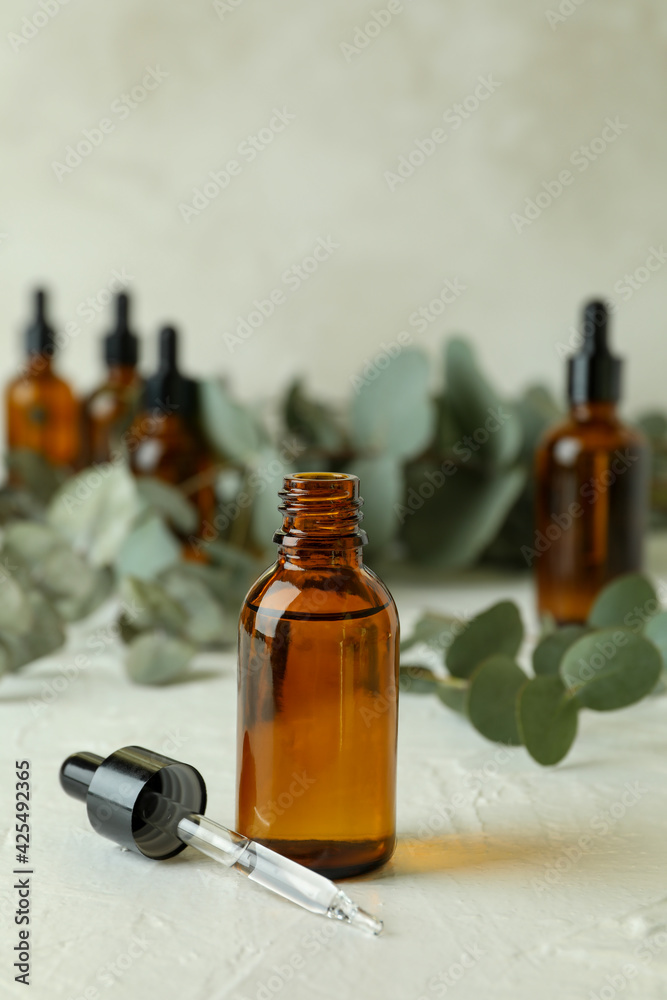 Bottles of eucalyptus oil and branches on white textured table Bottles of eucalyptus oil and branches on white textured table
