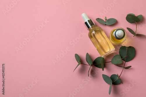Bottles of eucalyptus oil and twigs on pink background
