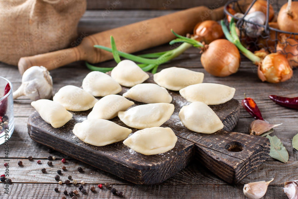 The process of making home-made dumplings. Molding dumplings. Raw homemade dumplings on a wooden board.