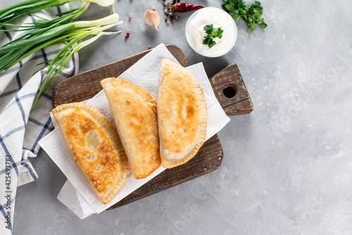 Foto Uzbek eastern Tatar cuisine, cheburek with meat and greens on a wooden board