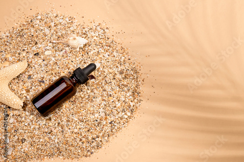 Glass brown bottle with a pipette in the sand. 
