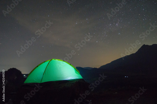 Camping fire under the amazing blurr starry sky with a lot of shining stars and clouds. Travel recreational outdoor activity concept. 