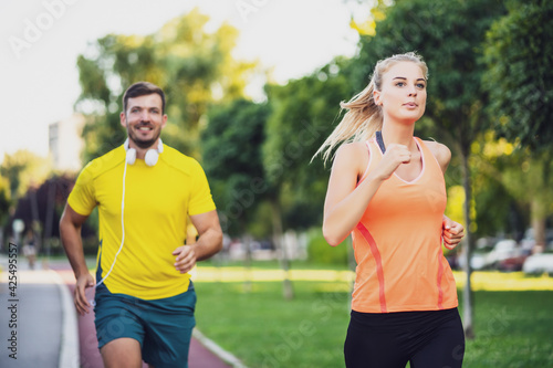 Young couple is jogging on running track in park.