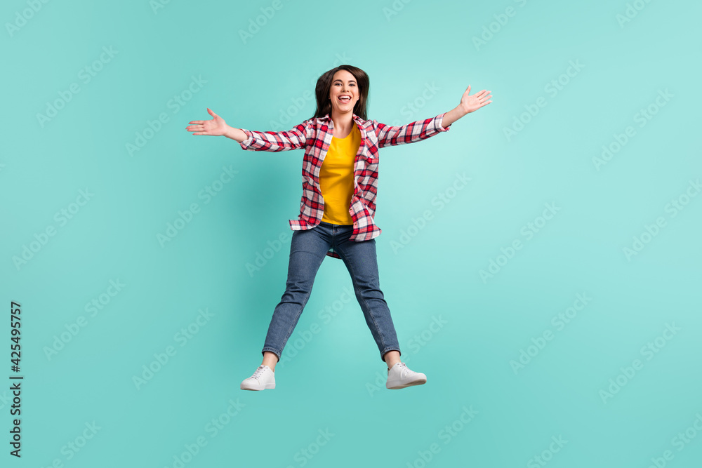 Full size photo of cheerful young lady jump up open hands welcome isolated on pastel teal color background Full size photo of cheerful young lady jump up open hands welcome isolated on pastel teal color background
