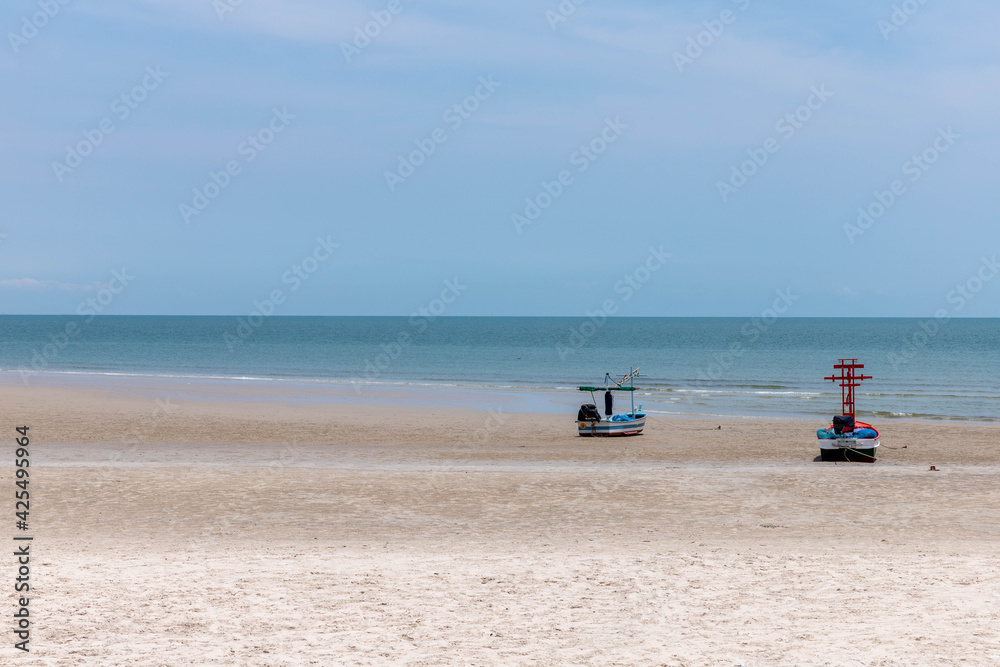 Two fishing boats moored on the shore in the blue sky. Two fishing boats moored on the shore in the blue sky.
