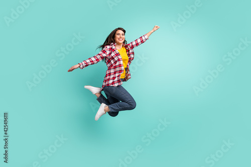 Full length body size view of attractive carefree cheerful girl jumping having fun free time isolated over bright teal turquoise color background