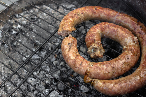Homemade sausage ring. Grilled meat. Large sausage. A product made from beef, pork or lamb. Grilled meat. Cook over hot coals on the grill. Cooking outdoors. Men's picnic food. Ruddy crust.
