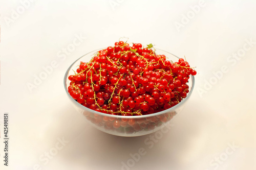 Large bowl of red currant with sprigs on a white background