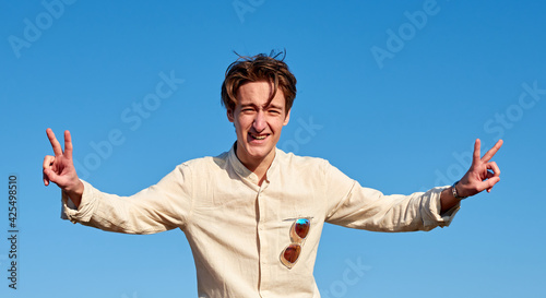 A Caucasian man from Spain making victory signs with both hands on clear sky background