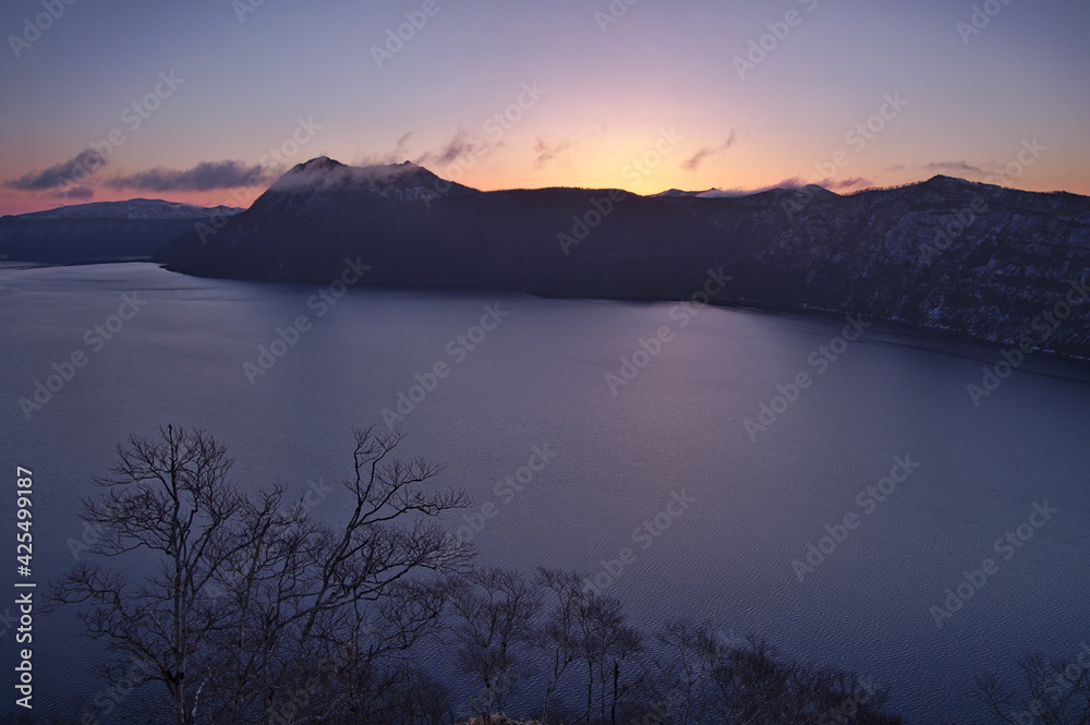 夜明けの湖とその周りの山並みのシルエット。の本の北海道の摩周湖。