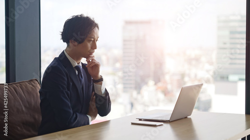 ノートパソコンを見ながら考えるビジネスマン
