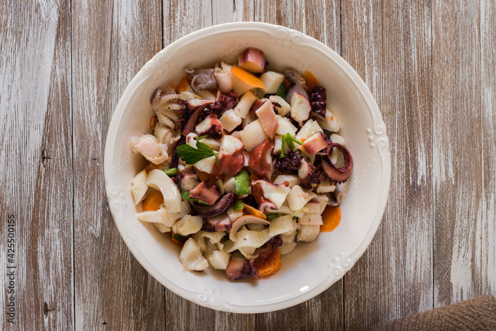 Seafood salad dressed and served in porcelain bowl on wooden background Seafood salad dressed and served in porcelain bowl on wooden background