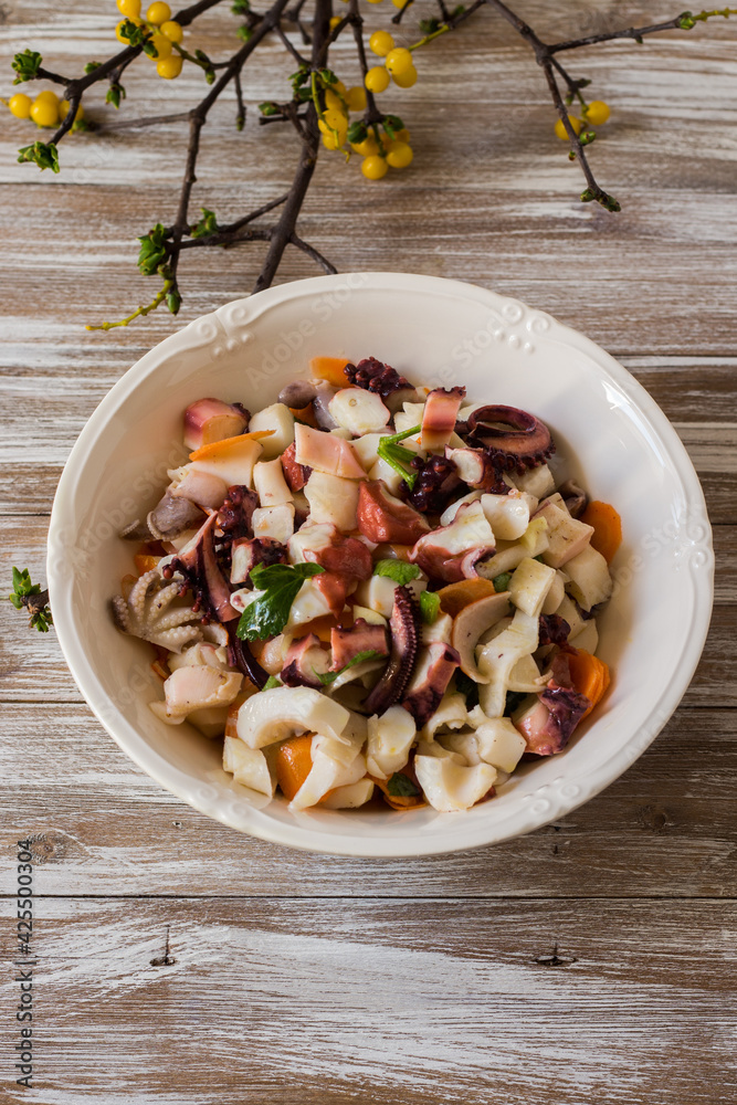 Seafood salad dressed and served in porcelain bowl on wooden background Seafood salad dressed and served in porcelain bowl on wooden background