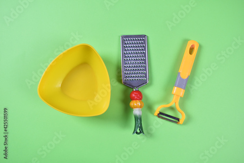Kitchen tools with yellow bowl on green background