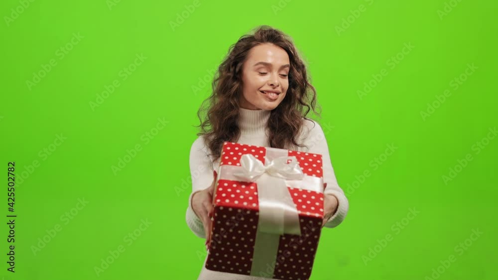 The woman is standing and looking at the camera. She is giving you a gift. She is standing on a green background. Green screen. 4K The woman is standing and looking at the camera. She is giving you a gift. She is standing on a green background. Green screen. 4K