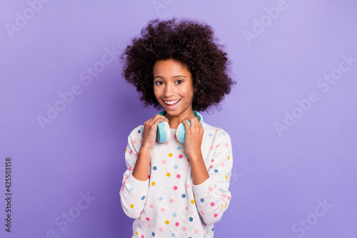 Photo portrait of small girl wearing blue headphones listening to music smiling isolated on pastel violet color background