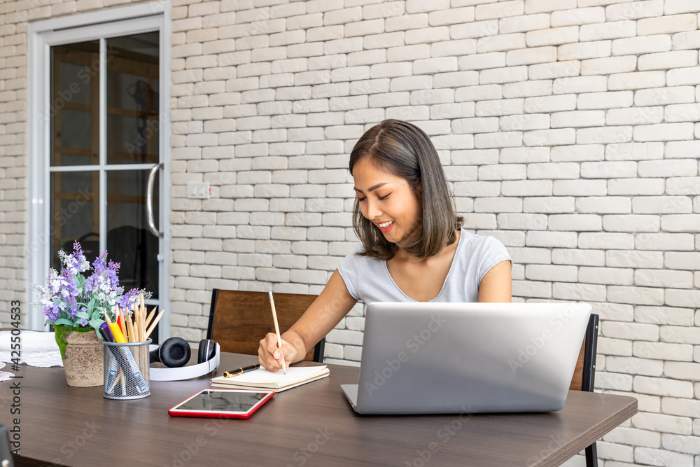 Portrait of Asian woman freelancer working at home, sitting at desk dining table in living room Portrait of Asian woman freelancer working at home, sitting at desk dining table in living room