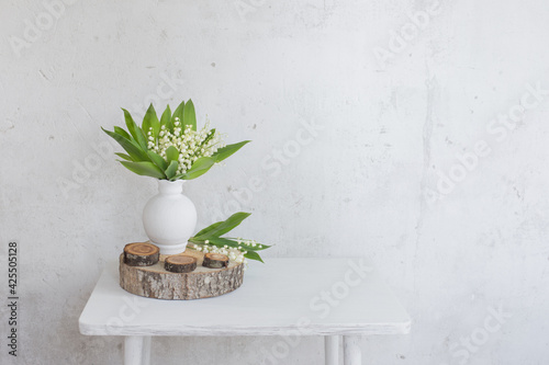 lily of the valley in vase on background old white wall