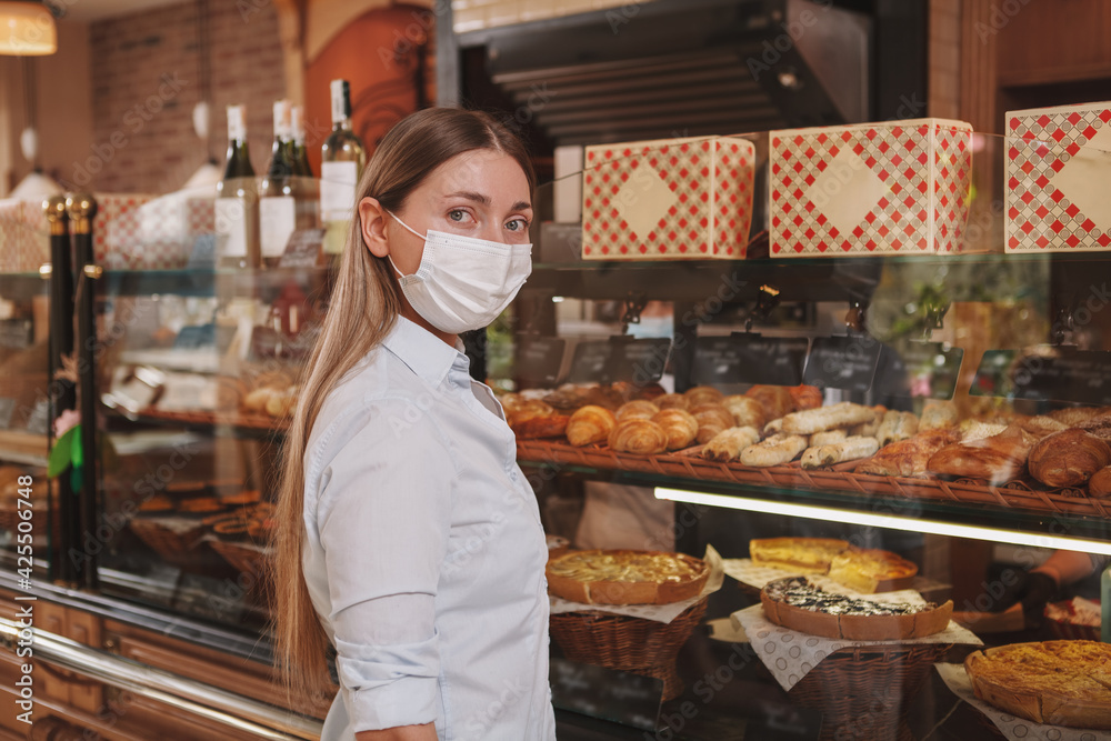 Woman looking to the camera, shopping at the bakery store, wearing medical face mask, copy space