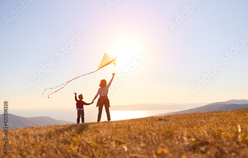 Happy family mother and son launch kite on nature at sunset
