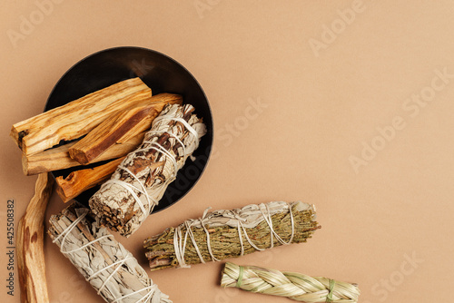 White sage, cedar, yerba santa, sweetgrass and Palo Santo sticks tied in bunch in metal bowl. Set of incense for fumigation. View from above. Organic holy tree incense from Latin America.