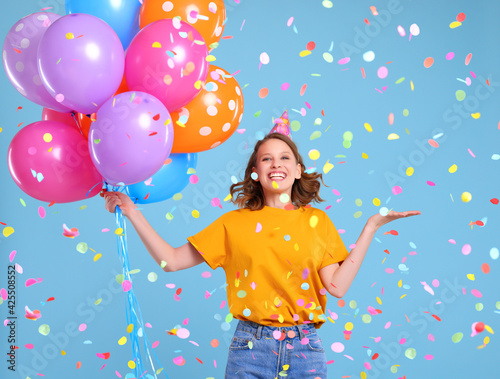 Delighted female with balloons dancing under confetti