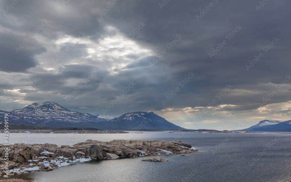 Landscape with the lake Akkajaure and mountains under a dark, overcast sky, Sweden. 