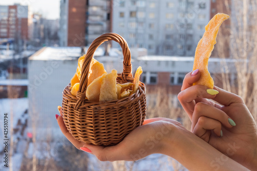 dried mango in a basket in the hands of a girl against the background of a winter city, the concept of vitamins in winter