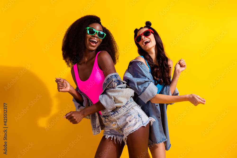Obraz premium Photo of two young girl happy positive smile have fun dance wear sunglass isolated over yellow color background