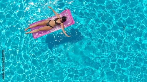 Girl on the airbed in the pool in the summer relaxes and plays with water photo