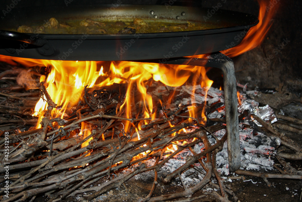 Paella on the fire cooked with the flames of burning branches. Traditional preparation of Paella. Paella on the fire cooked with the flames of burning branches. Traditional preparation of Paella.