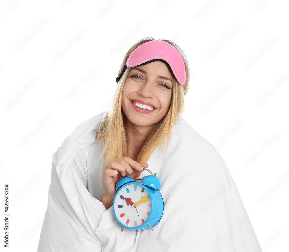 Young woman in sleeping mask wrapped with blanket holding alarm clock on white background Young woman in sleeping mask wrapped with blanket holding alarm clock on white background