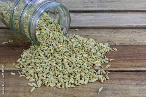 Dried organic fennel seeds or saunf in a glass jar on wooden background.