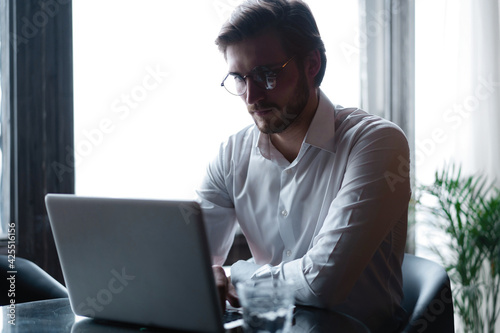 Young successful businessman working on a laptop while sitting in cafe
