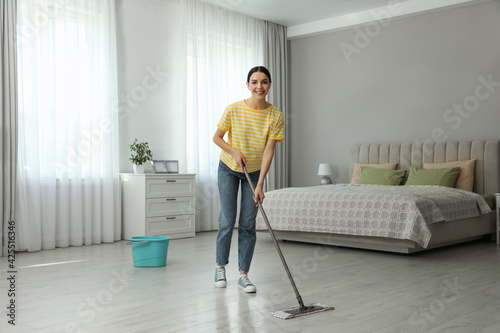 Woman cleaning floor with mop at home