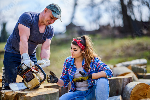 Lumberjack teaches his apprentice how to use the chainsaw