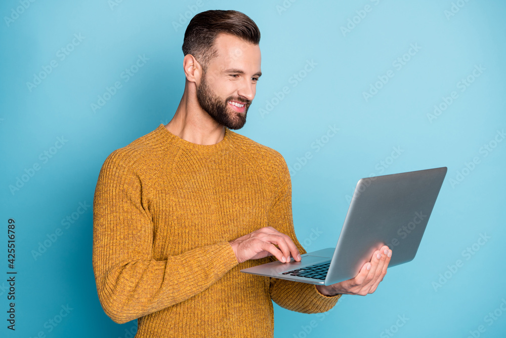 Portrait of nice attractive focused cheerful guy employee using laptop programming isolated over bright blue color background - obrazy, fototapety, plakaty 
