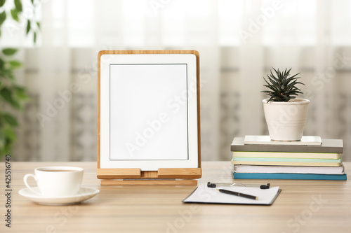 Modern tablet, cup of coffee and stationery on wooden table indoors. Space for design
