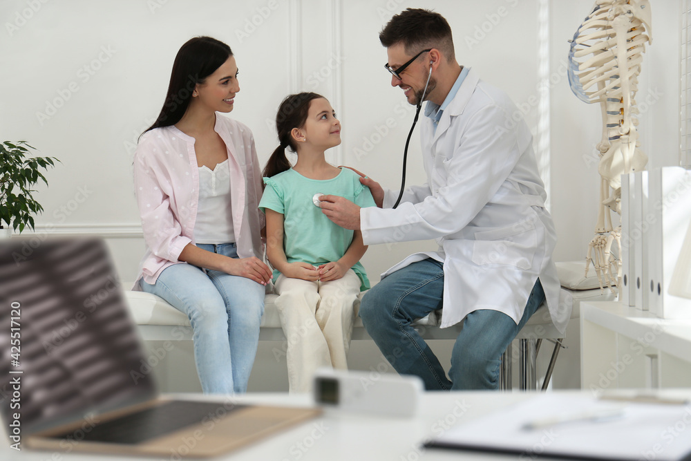 Obraz premium Mother with daughter visiting pediatrician in hospital. Doctor examining little girl