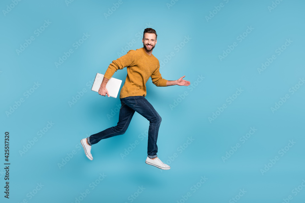Full length body size view of nice cheerful skilled successful guy jumping running carrying laptop isolated on bright blue color background