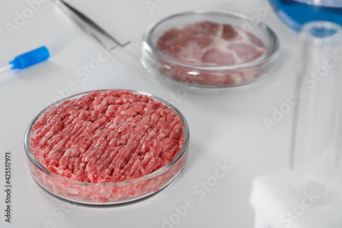 Petri dish with raw minced cultured meat on white table, space for text