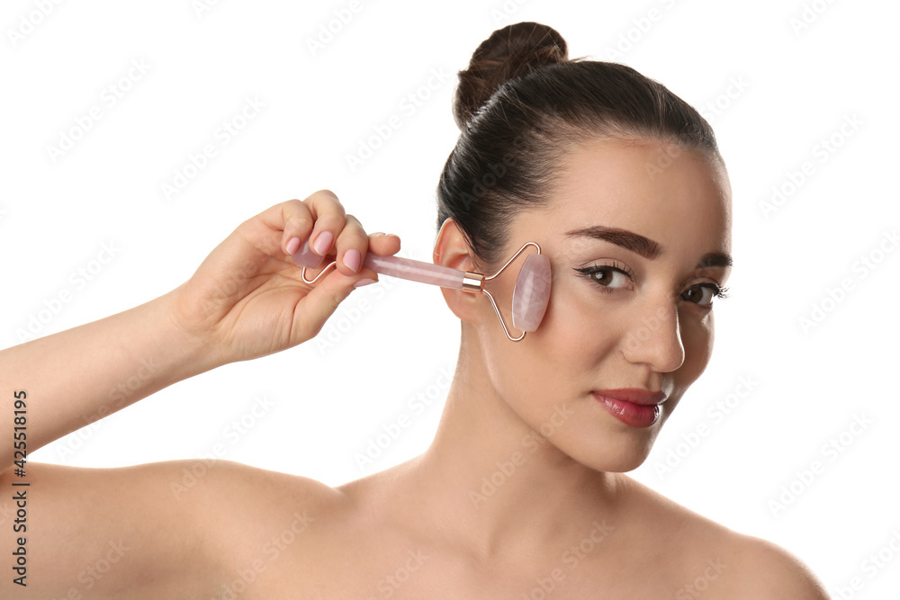 Woman using natural pink quartz face roller on white background Woman using natural pink quartz face roller on white background