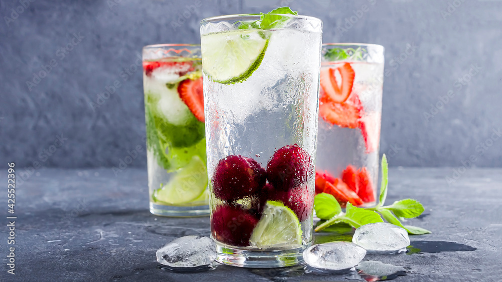 Three glass of refreshing cool detox drink with strawberry, lime, cherry and mint on blue background. Various summer lemonades or ice tea. Mojito cocktails with ice cubes. Healthy eating. Three glass of refreshing cool detox drink with strawberry, lime, cherry and mint on blue background. Various summer lemonades or ice tea. Mojito cocktails with ice cubes. Healthy eating.