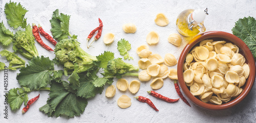 Italian handmade pasta Orecchiette with turnip leaves and tops or cima di rapa with chili pepper, olive oil on white table. Recipes and ingredients of southern Italy, Puglia. Internet banner