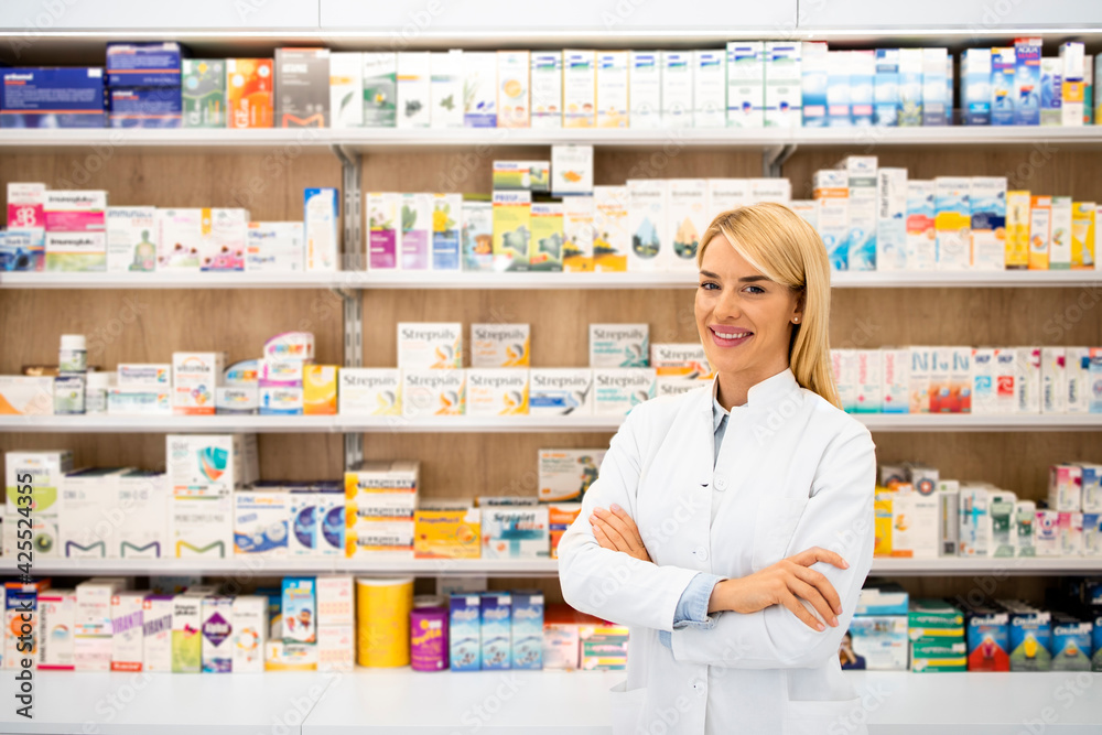 Portrait of smiling female caucasian pharmacist standing in drug store with arms crossed.