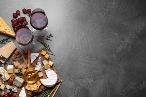 Cheese plate with honey, grapes and nuts on grey table, flat lay, Space for text