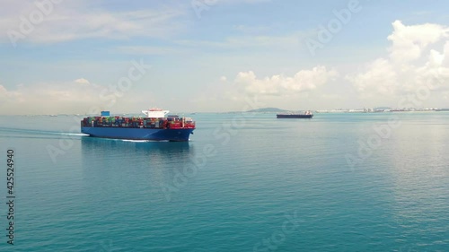 A large container ship for transporting goods near the port of Singapore. A container ship carries cargo across the ocean. Transportation. Delivery. Logistics. Aerial 4K shot.