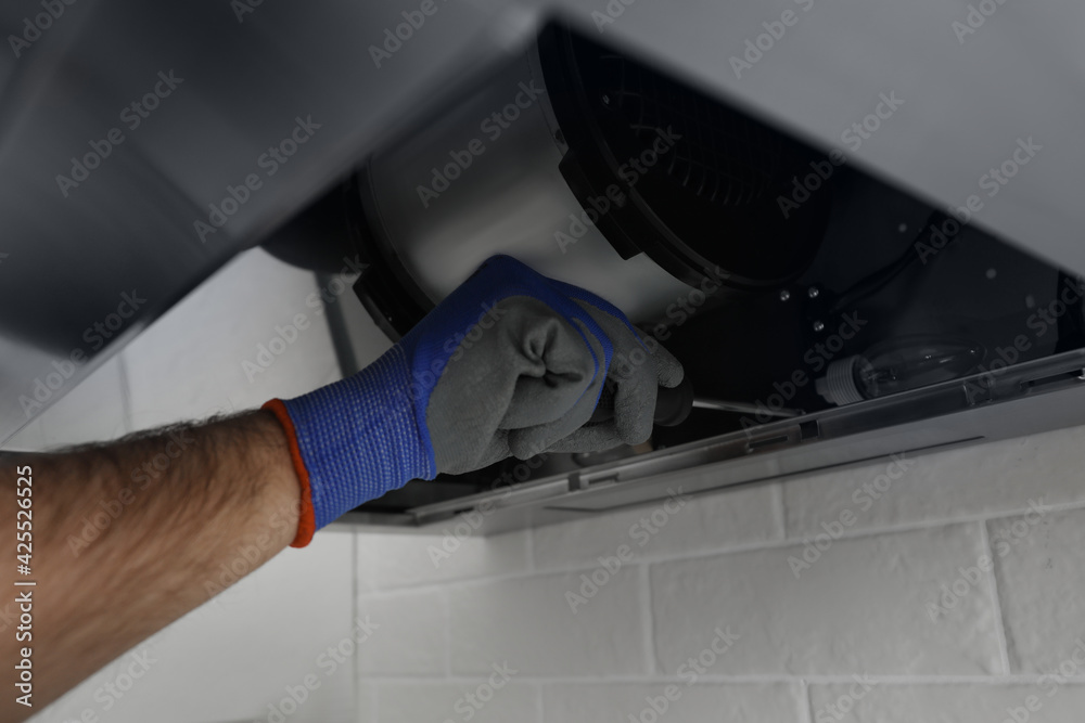 Worker repairing modern cooker hood indoors, closeup